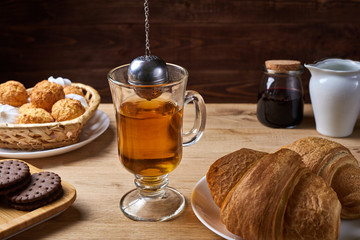 Hot tea put on table, drink breakfast in the morning day, breakfast with tea strainer and sweets on wooden table