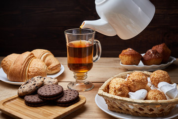 Hot tea put on table, drink breakfast in the morning day, breakfast with croissants and sweets on wooden table