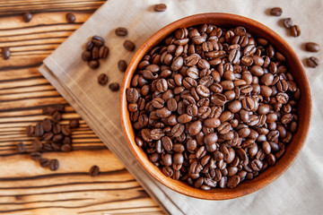 Wooden plate with roasted coffee beans on the wooden table