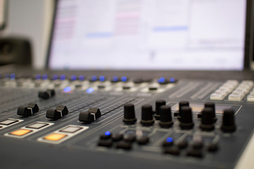 Professional audio mixing console with faders and adjustment knobs.