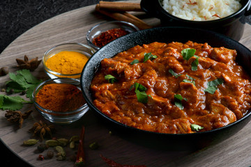 chicken curry with spices and rice on a dark background