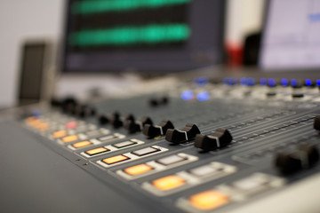 Professional audio mixing console with faders and adjustment knobs.