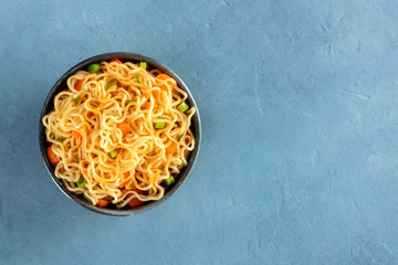 Instant noodles with carrot, scallions, and a sauce, a vegetable soba bowl, overhead shot with copy...