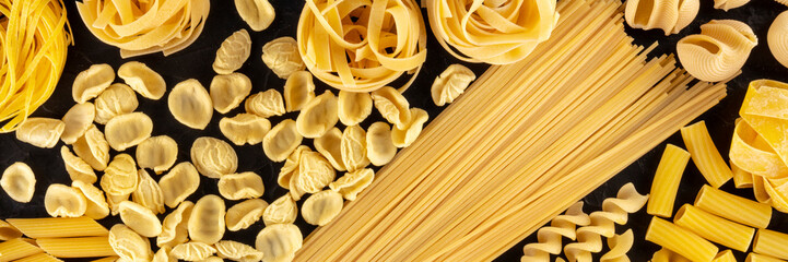 Italian pasta, a flat lay panoramic overhead shot of many different pasta sorts on a black...