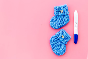 Positive pregnancy test. Baby boy concept with blue accessories on pink background top-down copy space