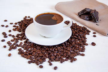 White cup of coffee stands on coffee beans