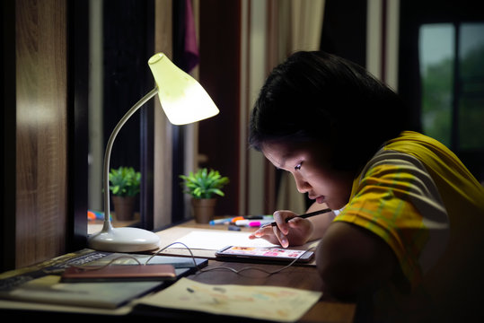 Asian Children Writing And Using Smartphone To Doing Homework At Home.Elementary Happy Kid Learning And Reading Book For Study To The Exam.Education Concept.