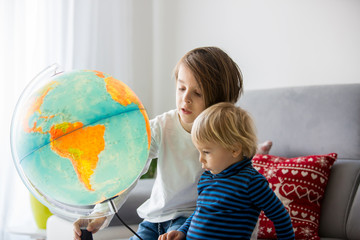Little children, brothers, looking at illuminated globe, exploring