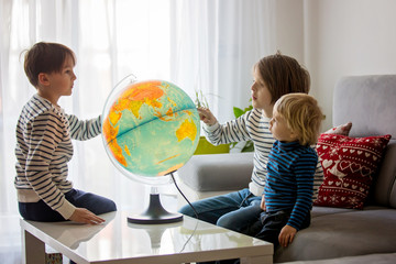Little children, brothers, looking at illuminated globe, exploring