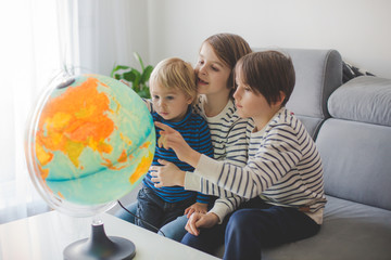 Little children, brothers, looking at illuminated globe, exploring