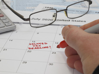 A handwritten note on a calendar shows the USA Internal Revenue Service IRS income tax filing deadline has moved from April 15 to July 15, 2020 due to the COVID-19 coronavirus pandemic.