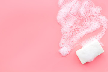 Soap bar with foam on pink background top-down copy space