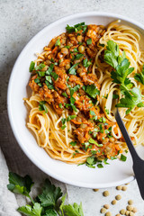 Vegetarian lentils bolognese pasta with parsley in white dish, top view. Healthy vegan food concept.