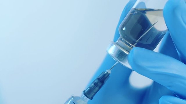 Collagen injection. Preventive healthcare. Doctor hands in gloves filling syringe from vial.