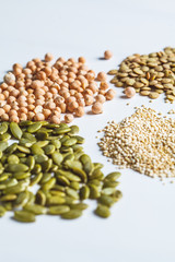 Flat lay of varied vegan protein. Dry chickpeas, lentils, quinoa and pumpkin seeds on a white background.