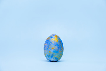 Happy Easter. One easter egg trendy colored classic blue, white and golden on blue background. Copy space. Minimal style