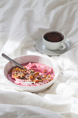 Berry smoothie bowl and a cup of coffee in a white bed. Wellness concept.