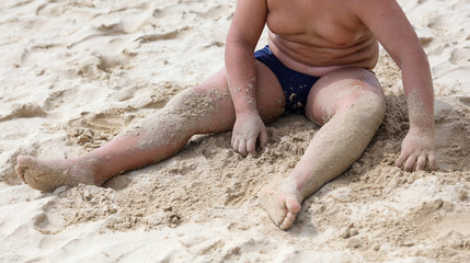 A boy is playing in the sand of a beach.