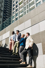 Members of multi-ethnic business team standing on steps, career and ambitions concept