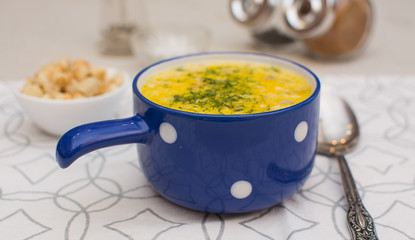 Puree soup with cheese and croutons in a blue ceramic bowl on a napkin.