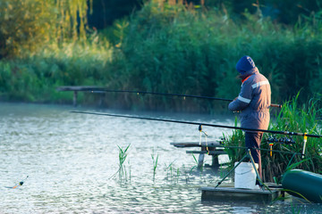 A fisherman is standing on the bridge and holding a fishing rod
