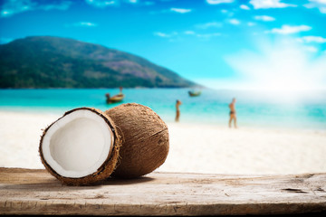Close up of coconut on wood table over summer beach background - obrazy, fototapety, plakaty
