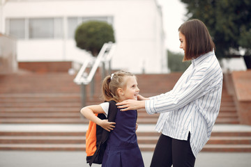 Mother and daughter. Family standing near school. Mom accompanies her child to school