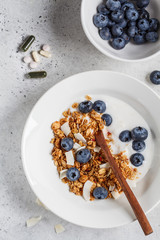 Breakfast and dietary supplements. Granola with yogurt and berries in white plate. Healthy lifestyle concept.
