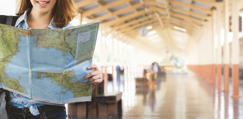 Young Asia woman wanderer with trendy look searching direction on location map while traveling in...