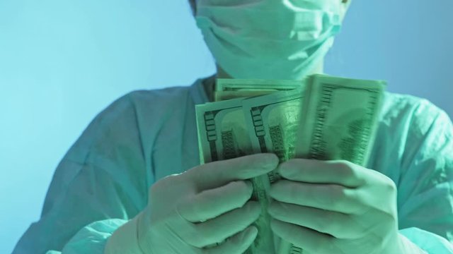 Medical expenses. Healthcare coverage. Anesthesiologist in protective equipment counting money.