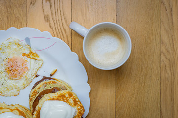 cup of coffee and pancakes on wooden background