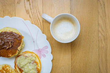 cup of coffee and pancakes on wooden background