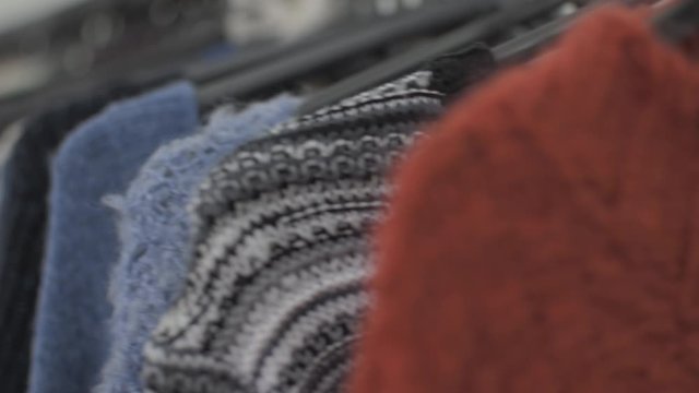Clothes and stuff in boutique store. Camera panning to the right. Focus change on the orange sweater.