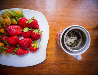 cup of tea with strawberries and physalis on a table 