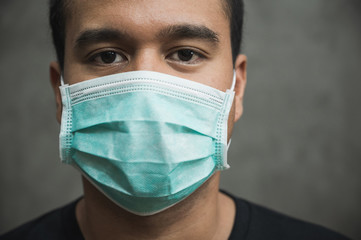 Close up young asian man wearing protection face mask against coronavirus.
