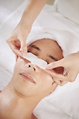 Fototapeta na wymiar Cosmetologist applying blackhead remover sticker on nose of male client