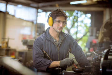 Portrait Industrial worker wearing safety uniform and safe helmet for work and control machines  with industry factory background.