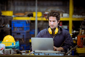 A Industry worker wearing safety uniform ,ear phone used radio communication with laptop for common...