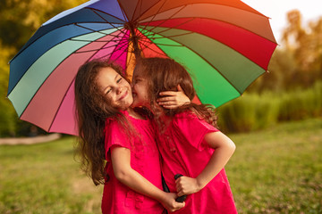 Happy sisters with umbrella having fun in garden