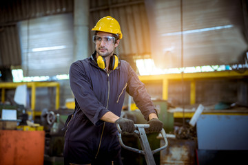 Industry worker wearing safety uniform ,glass , ear phone take a steel plate to make a new produce...