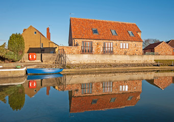 Naklejka premium Houses and boat next to a river with reflection