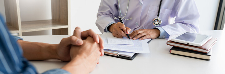 patient listening intently to a male doctor explaining patient symptoms or asking a question as they discuss paperwork together in a consultation