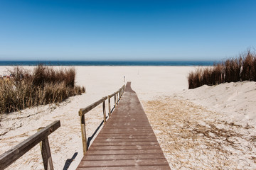Wooden pathway to the wide sand beach, sunny day, Juist, Germany