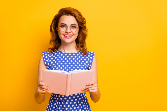 Photo of beautiful pretty wavy lady hold book hands excited reader best hobby free time spending wear specs polka-dot blue white shirt isolated yellow color background