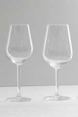 Two empty wine glasses  for red and  white wine in white grey shades