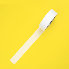 Round roll of white duct tape, adhesive tape on a yellow background.