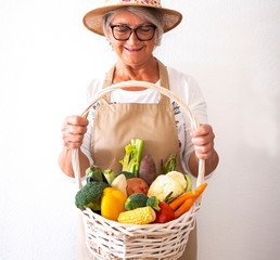 A happy people senior woman holds a basket with the crop from her vegetable garden. Rich assortment...