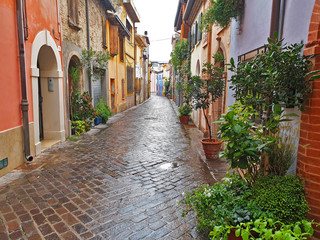 A colorful, narrow, deserted street in Rimini on a rainy, overcast day.