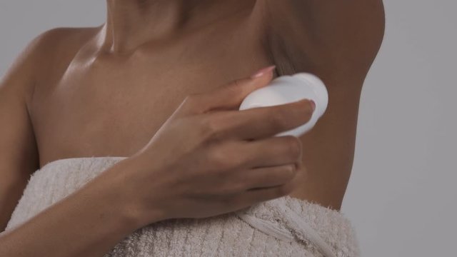 Woman applying deodorant on her armpit. Body care concept. Isolated, on white background