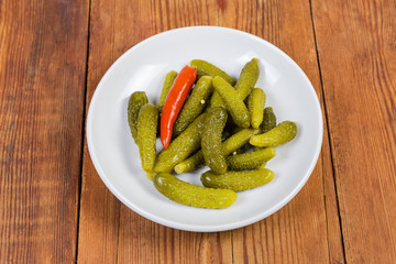 Pickled gherkins on white saucer on the rustic table